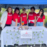 A group of Junior League members smile at you from a recruitment table.