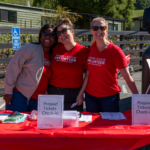 Junior League members smile at you while staffing a table.